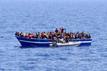 italian-navy-a-boat-filled-with-migrants-receives-aid-from-an-italian-navy-motor-boat